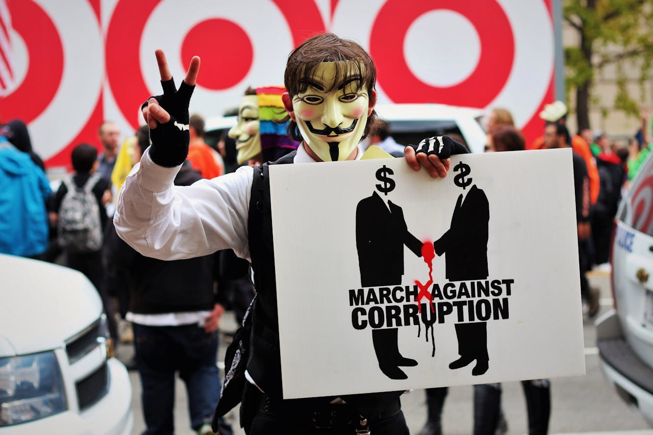our-services-2 A protester wears a Guy Fawkes mask holding a sign at a rally against corruption in Washington, DC.